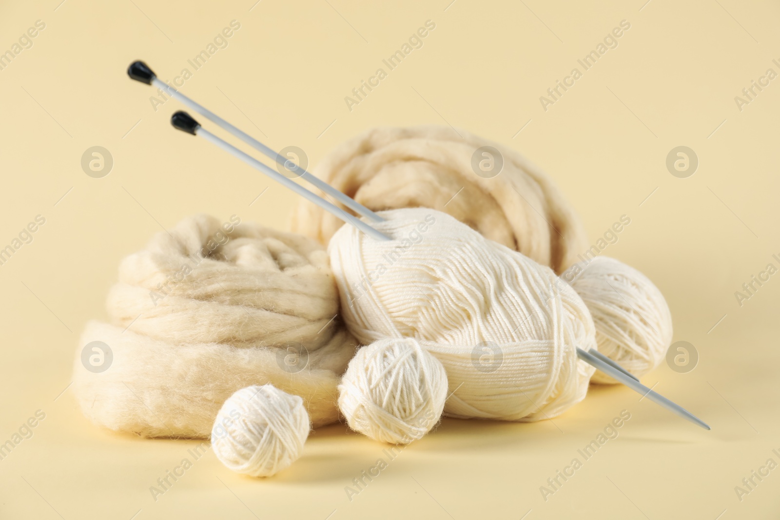 Felting wool and knitting yarn with needles on beige background, closeup Photo of Felting wool and knitting yarn with needles on beige background, closeup