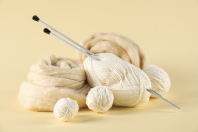 Photo of Felting wool and knitting yarn with needles on beige background, closeup