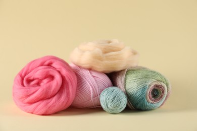 Photo of Felting wool and knitting yarn on beige background, closeup