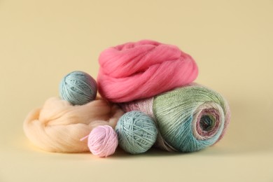 Photo of Felting wool and knitting yarn on beige background, closeup
