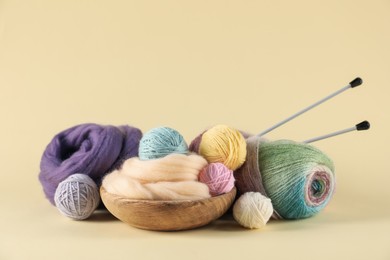 Photo of Felting wool and knitting yarn with needles on beige background. Space for text