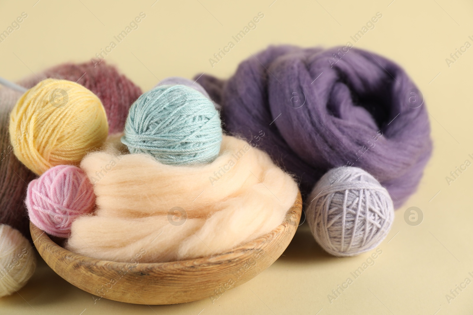 Felting wool and knitting yarn on beige background, closeup Photo of Felting wool and knitting yarn on beige background, closeup