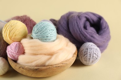Photo of Felting wool and knitting yarn on beige background, closeup