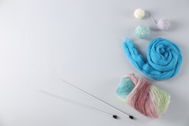 Photo of Felting wool and knitting yarn with needles on light background, flat lay. Space for text
