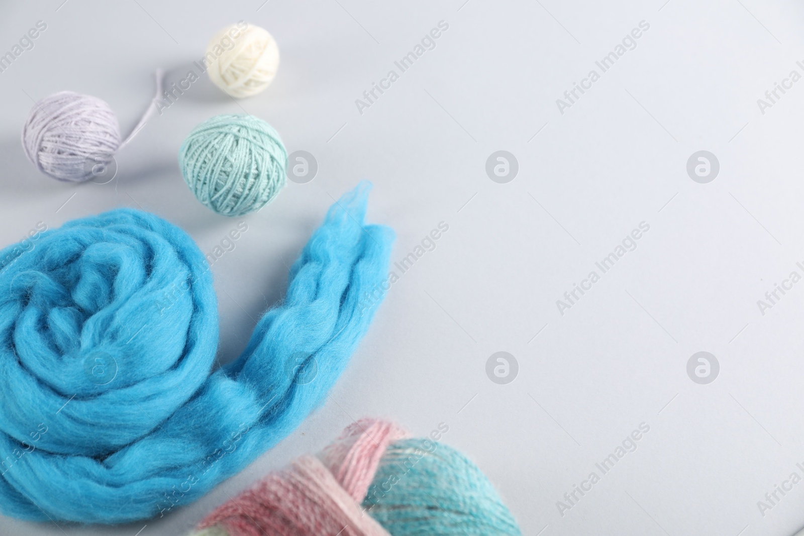 Felting wool and knitting yarn on light background, flat lay. Space for text Photo of Felting wool and knitting yarn on light background, flat lay. Space for text