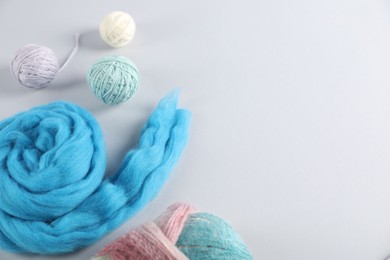 Photo of Felting wool and knitting yarn on light background, flat lay. Space for text