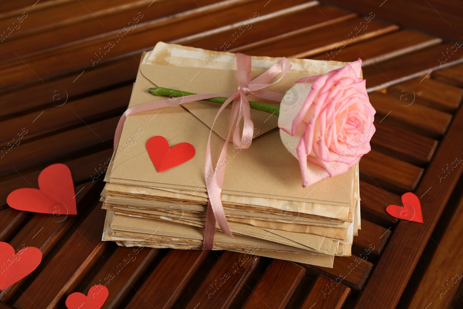 Stack of love letters, rose flower and paper hearts on wooden table indoors, above view Photo of Stack of love letters, rose flower and paper hearts on wooden table indoors, above view