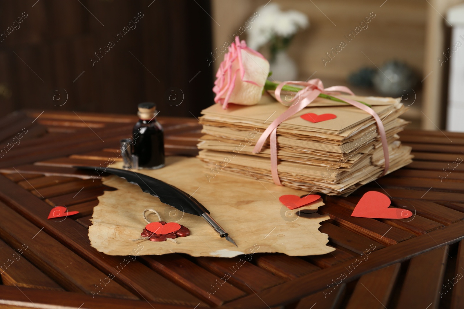 Stack of love letters, parchment sheet, ink, quill, rose flower and red hearts on wooden table indoors, closeup Photo of Stack of love letters, parchment sheet, ink, quill, rose flower and red hearts on wooden table indoors, closeup