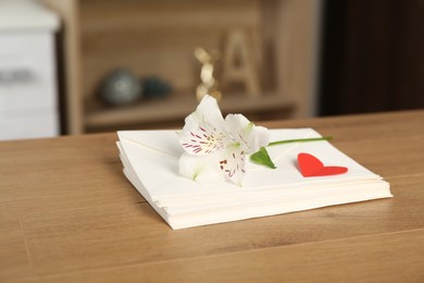 Photo of Stack of love letters, red heart and flower on wooden table indoors, closeup
