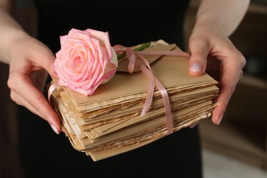 Photo of Woman with stack of love letters and rose flower indoors, closeup