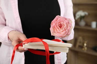 Photo of Woman with stack of love letters and rose flower indoors, closeup