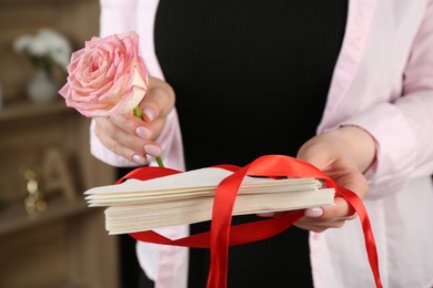 Photo of Woman with stack of love letters and rose flower indoors, closeup