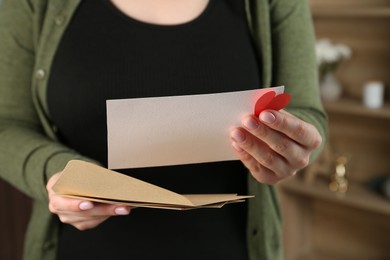 Photo of Woman with love letter, envelopes and red heart indoors, closeup