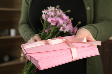 Photo of Woman with stack of love letters and flowers indoors, closeup