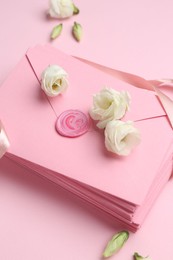 Photo of Stack of love letters and flowers on pink background, above view