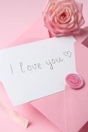 Photo of Stack of letters, card with phrase I Love You and rose flower on pink background, closeup