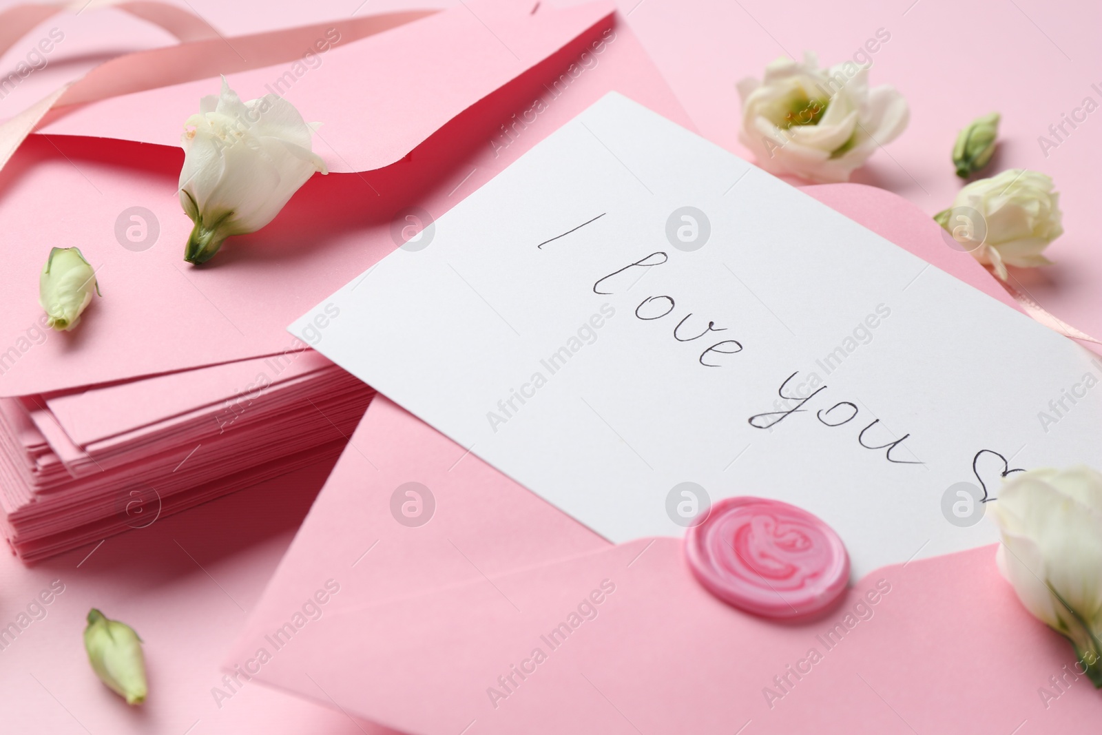 Stack of letters, card with phrase I Love You and flowers on pink background, closeup Photo of Stack of letters, card with phrase I Love You and flowers on pink background, closeup