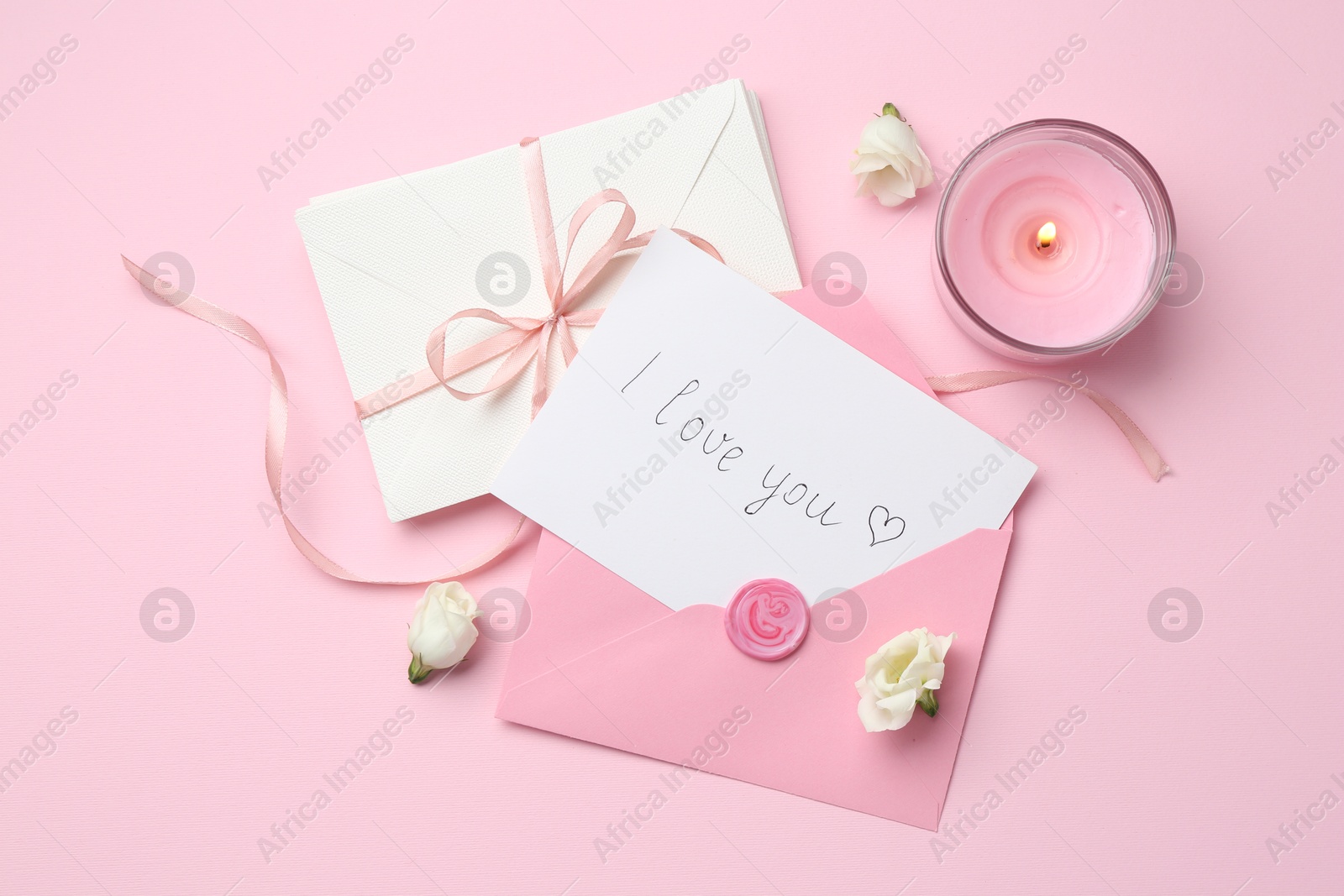 Stack of letters, card with phrase I Love You, burning candle and flowers on pink background, flat lay Photo of Stack of letters, card with phrase I Love You, burning candle and flowers on pink background, flat lay