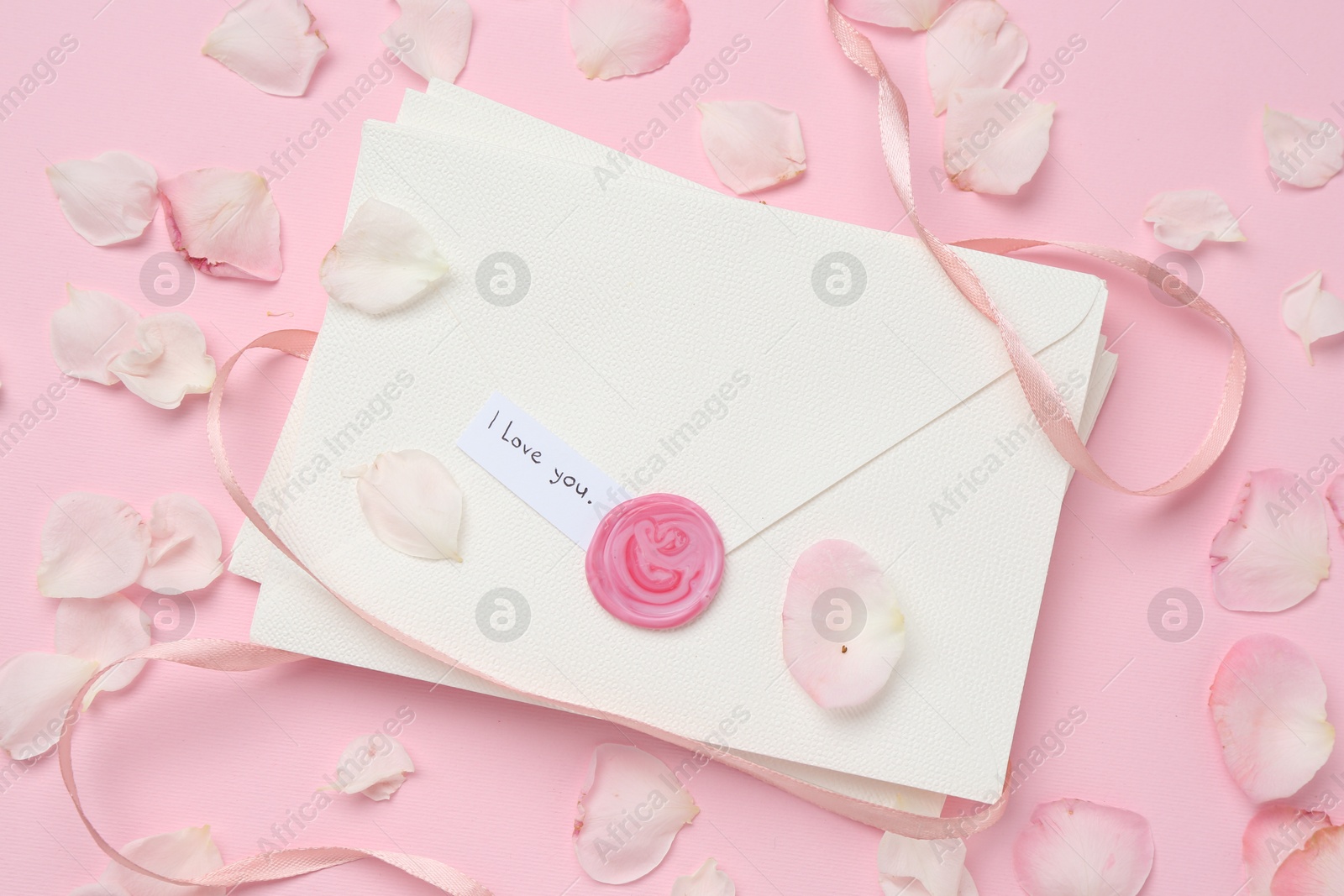 Stack of letters with phrase I Love You and petals on pink background, flat lay Photo of Stack of letters with phrase I Love You and petals on pink background, flat lay