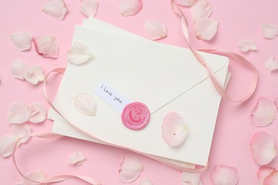 Photo of Stack of letters with phrase I Love You and petals on pink background, flat lay