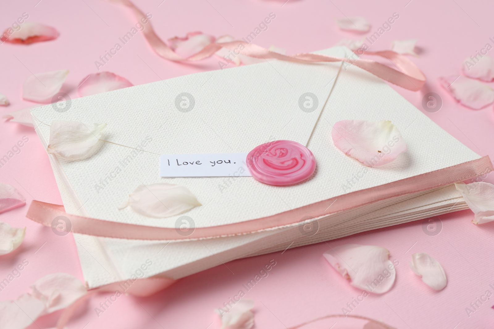 Stack of letters with phrase I Love You and petals on pink background, closeup Photo of Stack of letters with phrase I Love You and petals on pink background, closeup