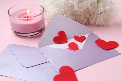 Photo of Love letters, red hearts, burning candle and flowers on pink background, closeup