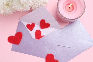 Photo of Love letters, red hearts, burning candle and flowers on pink background, flat lay