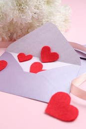 Photo of Love letter. Envelope, red hearts, ribbon and flowers on pink background, closeup