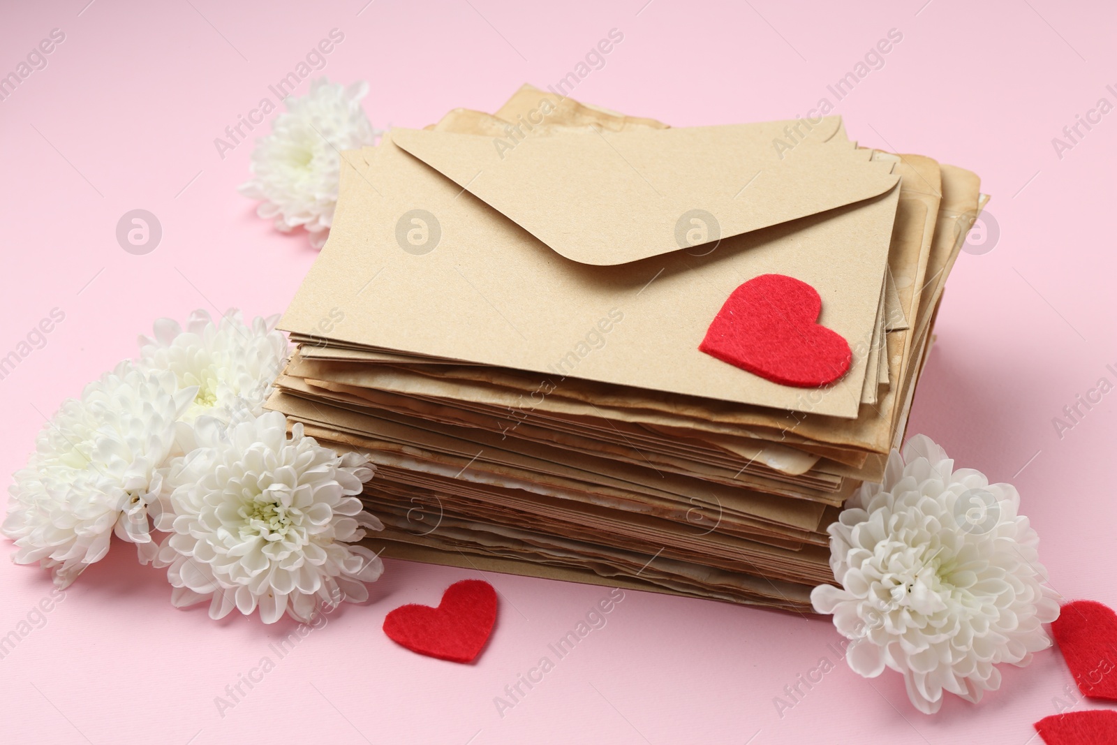 Stack of love letters, flowers and red hearts on pink background Photo of Stack of love letters, flowers and red hearts on pink background