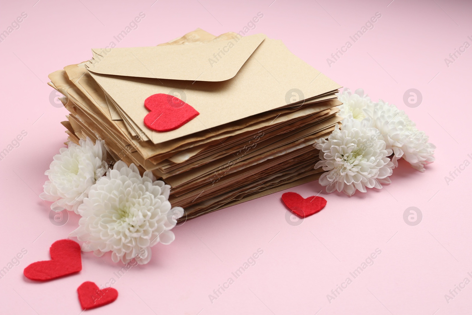 Stack of love letters, flowers and red hearts on pink background Photo of Stack of love letters, flowers and red hearts on pink background