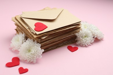 Photo of Stack of love letters, flowers and red hearts on pink background