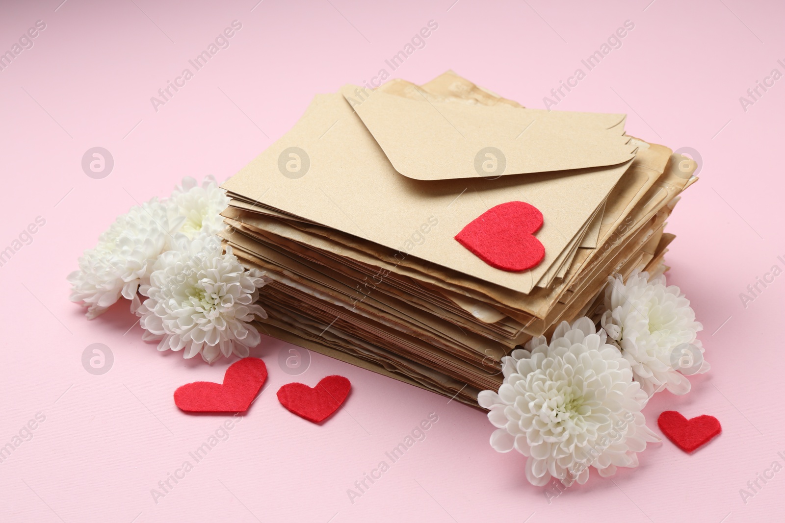 Stack of love letters, flowers and red hearts on pink background Photo of Stack of love letters, flowers and red hearts on pink background