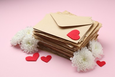 Photo of Stack of love letters, flowers and red hearts on pink background