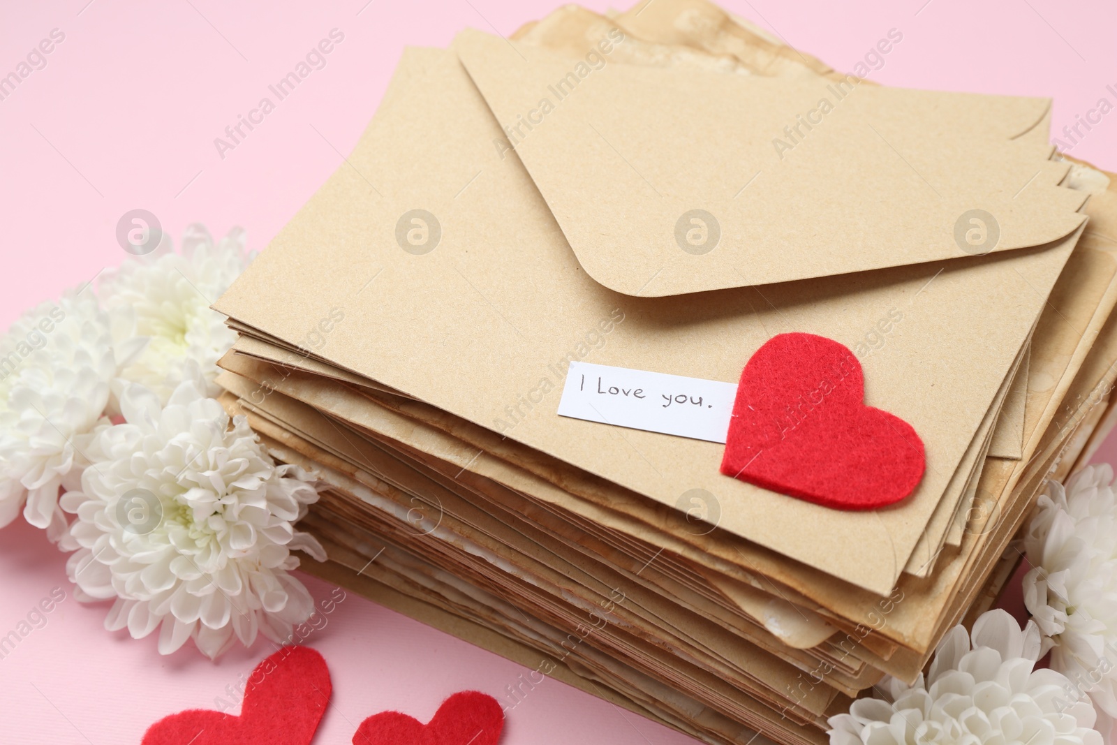 Stack of letters with phrase I Love You, flowers and red hearts on pink background, above view Photo of Stack of letters with phrase I Love You, flowers and red hearts on pink background, above view
