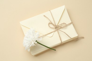 Photo of Stack of love letters and flower on beige background, top view