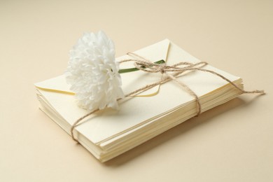 Photo of Stack of love letters and flower on beige background, closeup