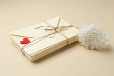 Photo of Stack of love letters, flower and red heart on beige background