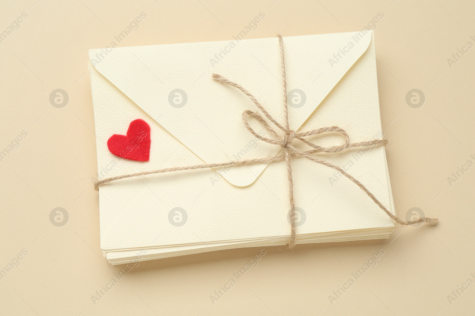 Stack of love letters and red heart on beige background, top view Photo of Stack of love letters and red heart on beige background, top view