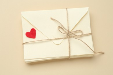 Photo of Stack of love letters and red heart on beige background, top view