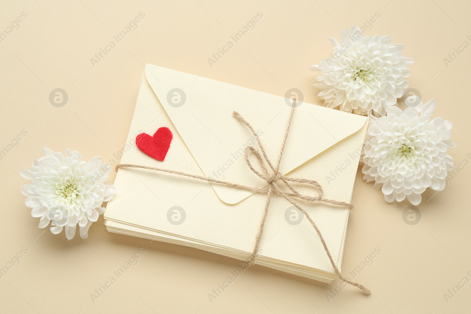 Stack of love letters, flowers and red heart on beige background, flat lay Photo of Stack of love letters, flowers and red heart on beige background, flat lay