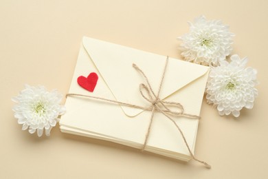 Photo of Stack of love letters, flowers and red heart on beige background, flat lay