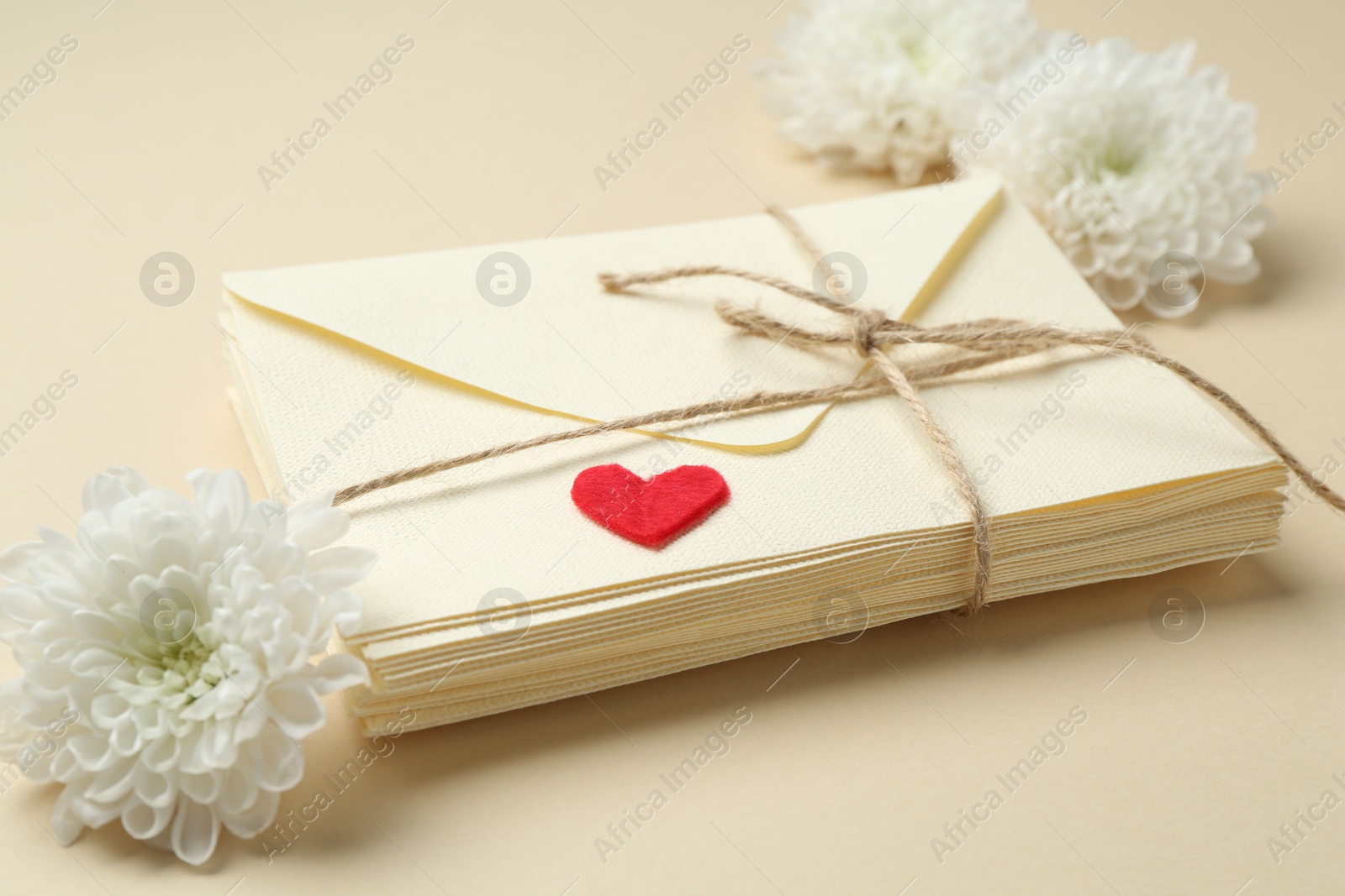 Stack of love letters, flowers and red heart on beige background, closeup Photo of Stack of love letters, flowers and red heart on beige background, closeup