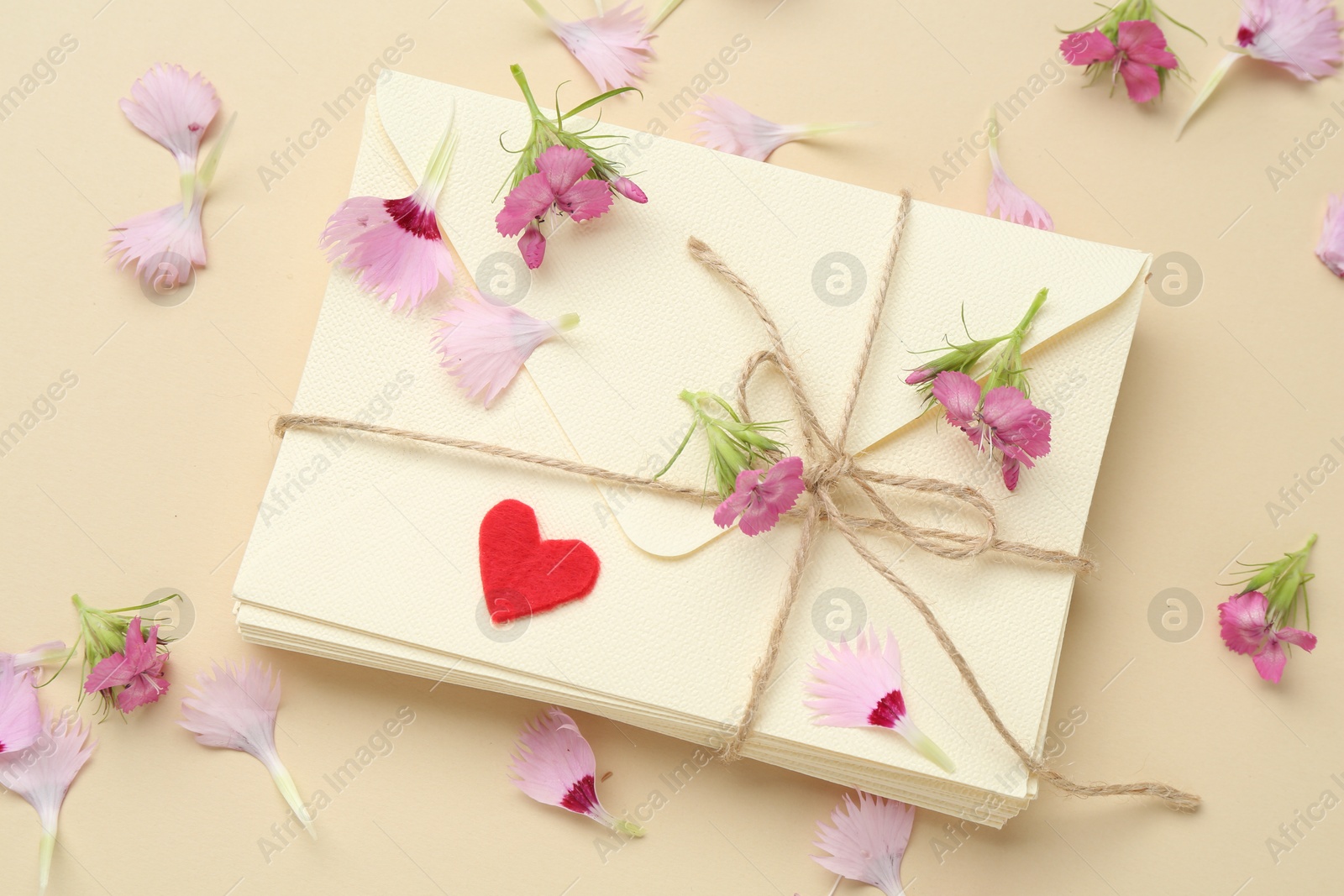 Stack of love letters, flowers and red heart on beige background, flat lay Photo of Stack of love letters, flowers and red heart on beige background, flat lay