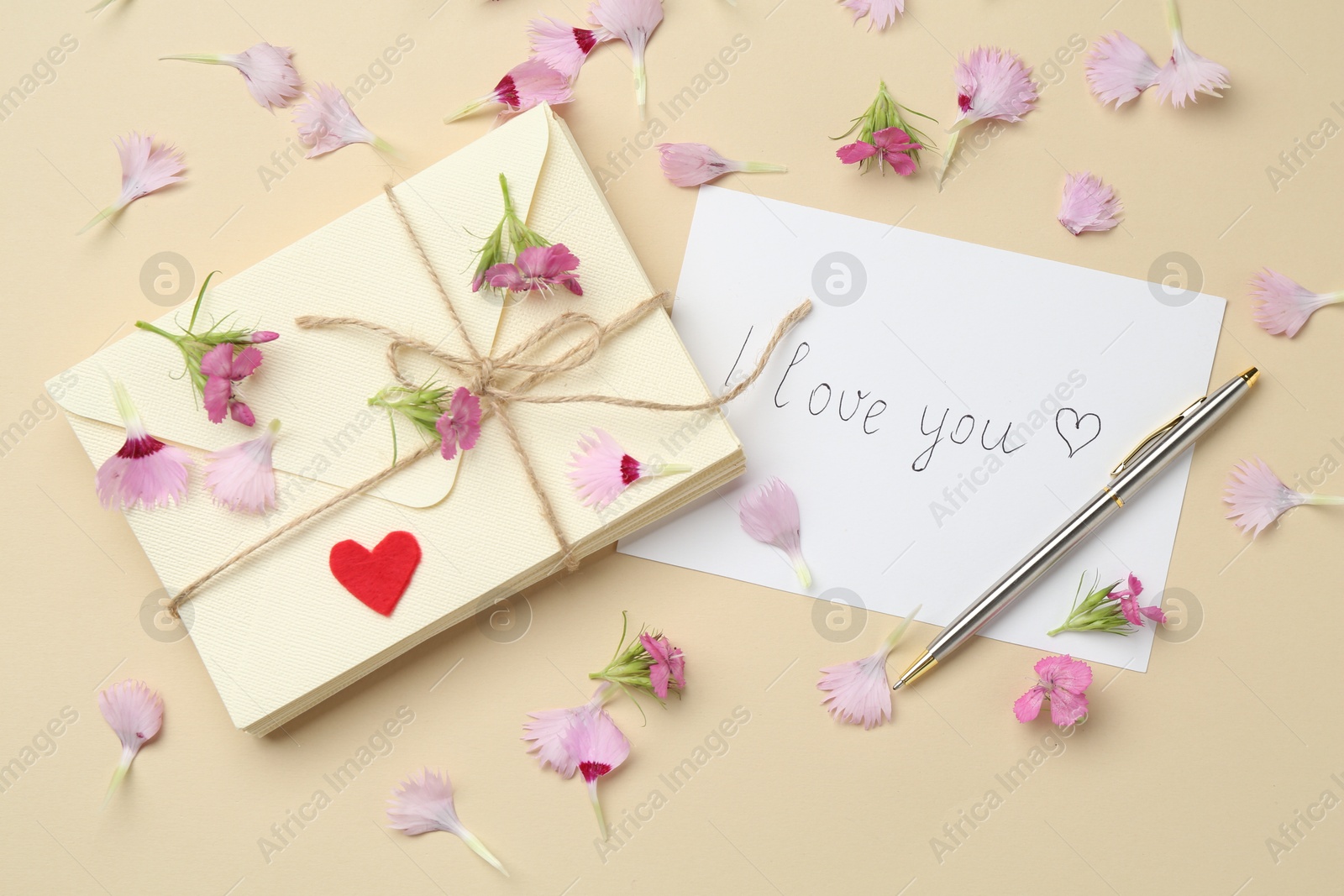 Stack of letters, card with phrase I Love You, pen and flowers on beige background, flat lay Photo of Stack of letters, card with phrase I Love You, pen and flowers on beige background, flat lay