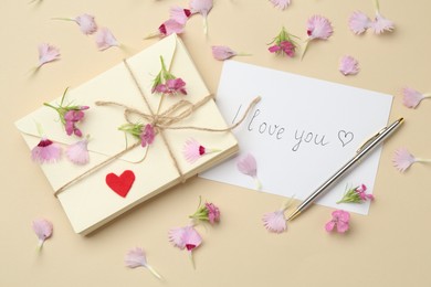 Photo of Stack of letters, card with phrase I Love You, pen and flowers on beige background, flat lay