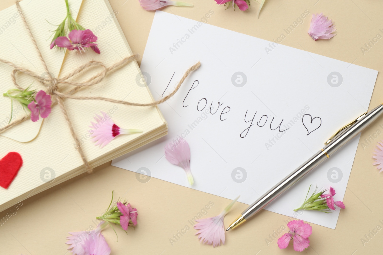 Stack of letters, card with phrase I Love You, pen and flowers on beige background, flat lay Photo of Stack of letters, card with phrase I Love You, pen and flowers on beige background, flat lay