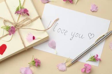 Photo of Stack of letters, card with phrase I Love You, pen and flowers on beige background, flat lay