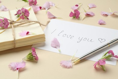 Photo of Stack of letters, card with phrase I Love You, pen and flowers on beige background, closeup