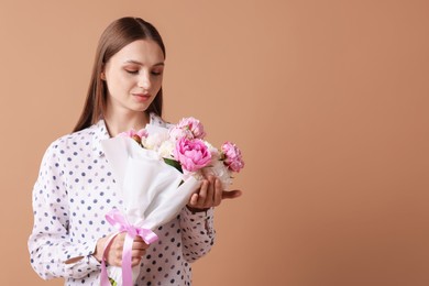 Photo of Woman with beautiful bouquet of peonies on dark beige background, space for text