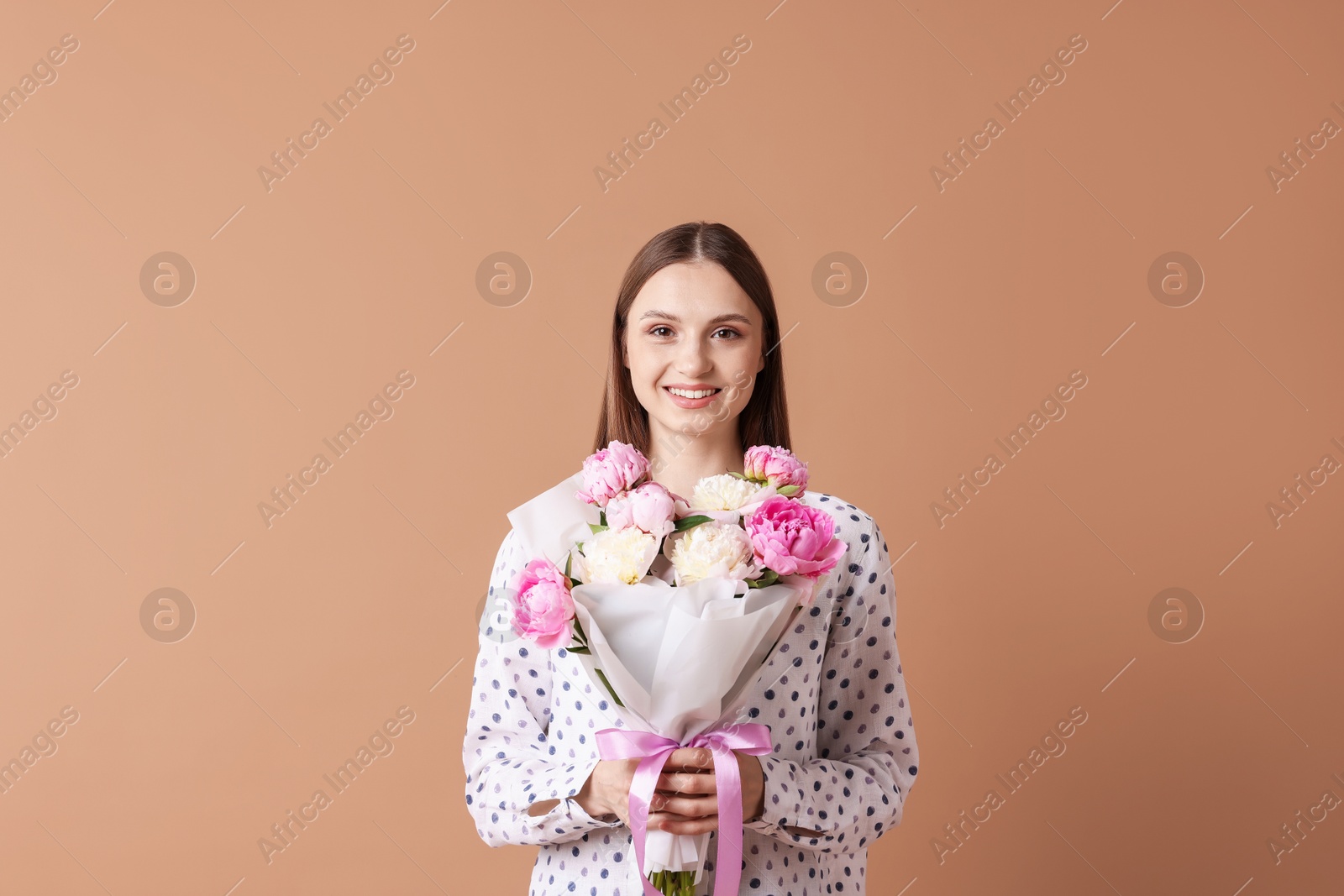 Woman with beautiful bouquet of peonies on dark beige background Photo of Woman with beautiful bouquet of peonies on dark beige background